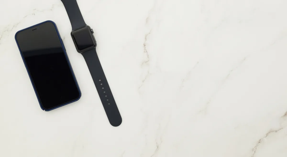 A smartphone and a smartwatch on a clean marble surface