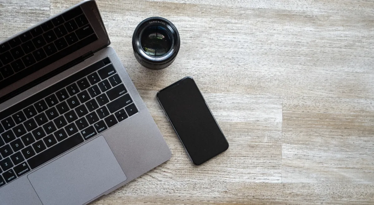 Overhead view of a laptop and a smartphone side by side on a wooden desk